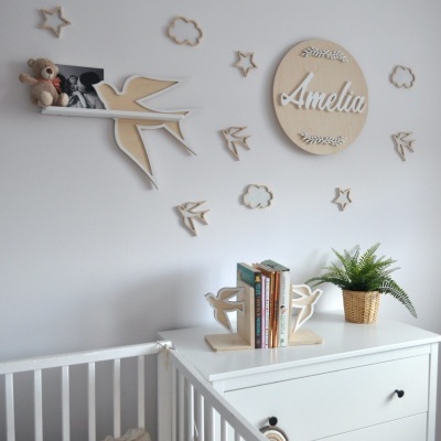 Decoração de quarto infantil com prateleira em forma de pássaro e nome 'Amelia' em círculo de madeira