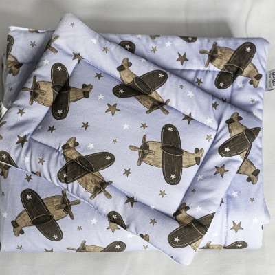 Conjunto de almofada e colcha em tecido azul claro com padrão de aviões castanhos e estrelas beges