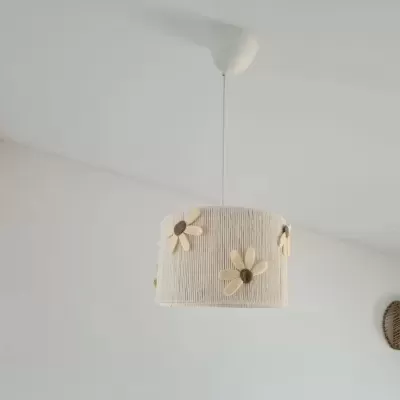 Lâmpada suspensa com cúpula bege com flores de tecido e cesta de vime na parede branca