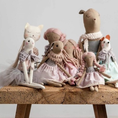 Bonecas de pano coloridas sentadas num banco de madeira