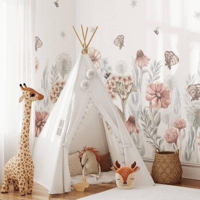 Tenda tipo tipi infantil branca com pompons rodeada de brinquedos e papel de parede floral.