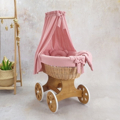 Carrinho de bebé de vime com tecidos cor de rosa e dossel