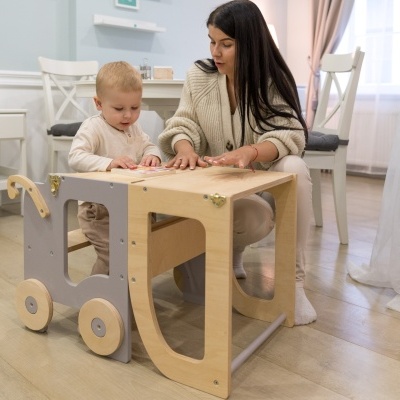 Mesa carrinho em madeira natural clara com rodas e dois tabuleiros numa sala clara