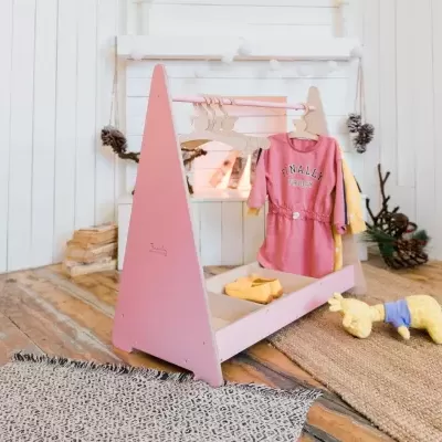 Berço de bebé rosa com roupa pendurada e boneco de peluche num ambiente decorado de Natal