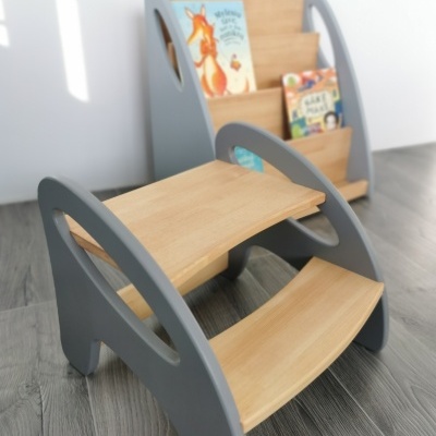 Móvel infantil cinzento e madeira clara com prateleiras em escada e suporte para livros