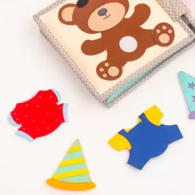 Brinquedo infantil em tecido com ursinho e peças coloridas destacadas