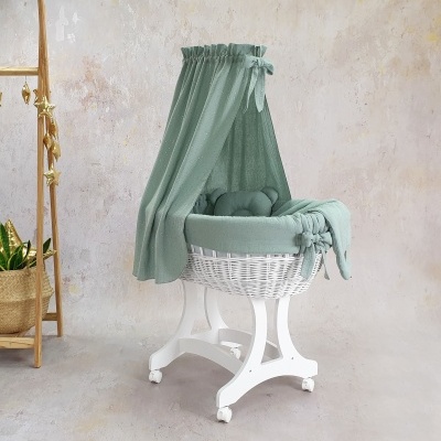 Berço de bebé em vime branco com dossel verde-água num ambiente interior