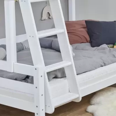 Cama branca com escadinha e roupa de cama cinza, almofadas castanha e azul, livro e decoração de parede