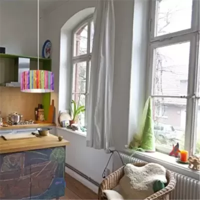 Cozinha com luminária colorida pendente, cadeira de vime e janela grande com cortinas brancas