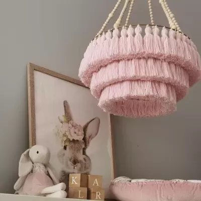 Candeeiro cor de rosa com franjas e decoração de quarto infantil com coelho e blocos de madeira