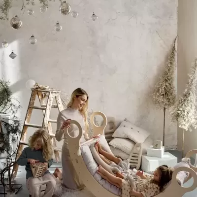 Cadeira de balanço infantil em madeira clara com almofada cinza e duas crianças