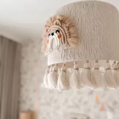 Abajur suspenso em tecido creme com franjas e decoração de leão