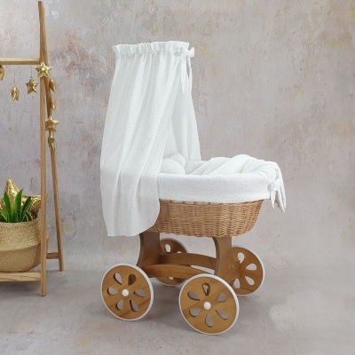 Carrinho de bebé em vime com tecido branco e estrutura de madeira