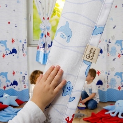 Cortinas infantis com padrão marinho azul e vermelho em quarto de crianças.