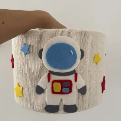 Cesta de tecido bege com astronauta e estrelas coloridas de feltro