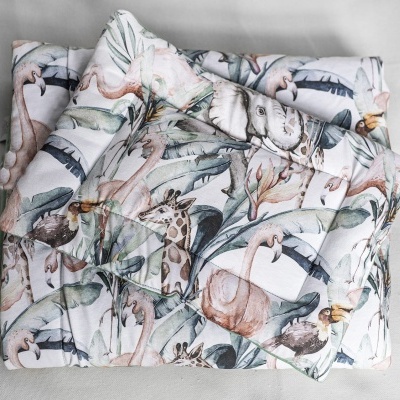 Cobertor acolchoado com padrão de animais da selva em tons pastel dobrado