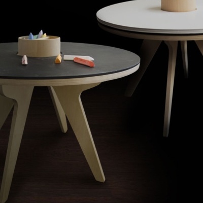 Mesas redondas em madeira clara com tampo preto e branco e giz colorido no centro