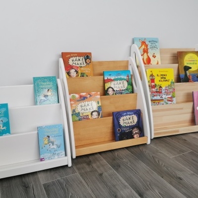 Três estantes de madeira para livros infantis com livros coloridos