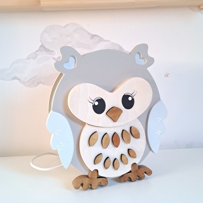 Abajur de coruja em madeira cinzenta e branca sobre superfície branca