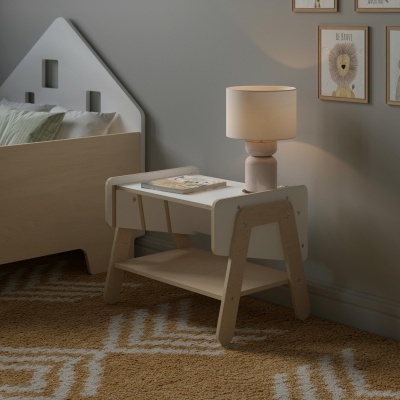 Mesa de cabeceira de madeira clara com candeeiro branco junto a cama infantil