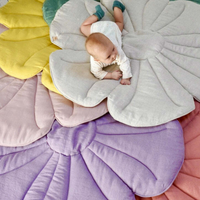 Tapetes almofadados em forma de pétalas coloridas com bebé deitado no centro.