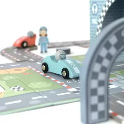 Brinquedo de corrida de madeira com carrinhos azul claro e vermelho numa pista com sinalização e bandeiras xadrez.