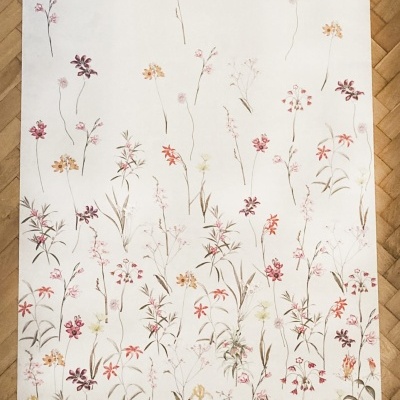 Tapete branco com padrão floral delicado em várias cores sobre chão de madeira parquet.