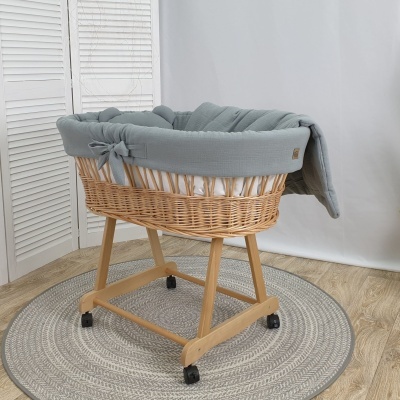 Berço de bebé em vime com acolchoado cinzento em ambiente interior