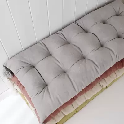 Colchões almofadados empilhados em várias cores pastel junto a uma parede branca