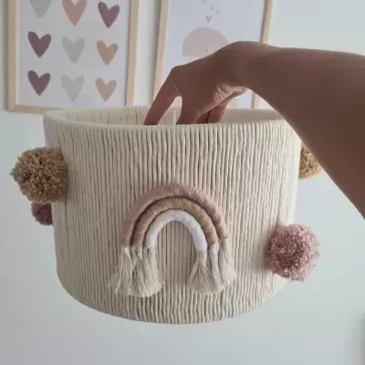 Cesto tecido creme com pompons e arco-íris bordado em ambiente decorado