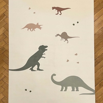Tapete bege com dinossauros coloridos e pegadas em chão de madeira