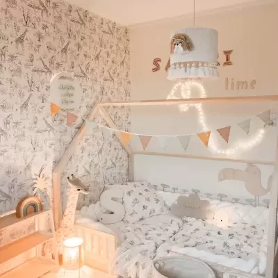 Quarto infantil com cama de madeira clara, papel de parede com desenhos de animais e candeeiro decorado