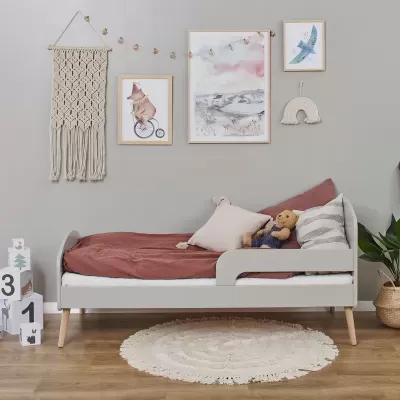 Quarto infantil com cama cinza, almofadas, ursinho e decoração de parede em macramé e quadros.