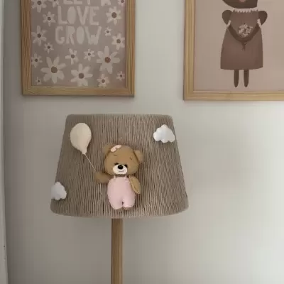 Abajur com urna e base em madeira, cúpula cinzenta com ursinho e balão, quadro com texto LET LOVE GROW ao fundo