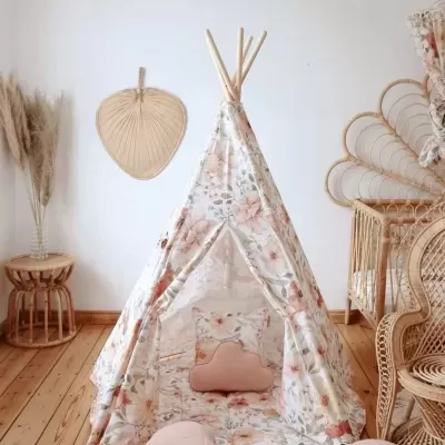 Tenda tipi infantil floral com almofadas rosas em chão de madeira