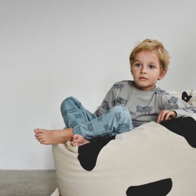 Criança sentada num puff estampado de panda num ambiente simples