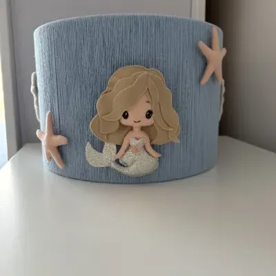 Cesto azul claro de tecido com decoração de sereia e estrelas-do-mar de feltro