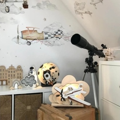 Relógio de parede em forma de avião e telescópio em ambiente com decoração de aviação