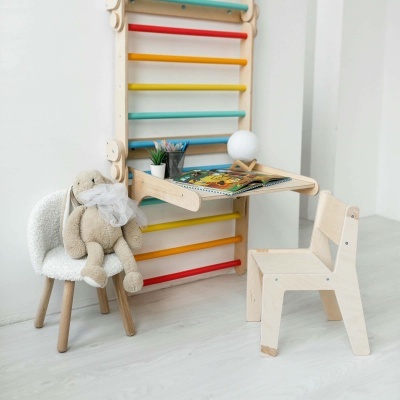 Mesa escolar de madeira clara suspensa com cadeira e brinquedo em zona infantil