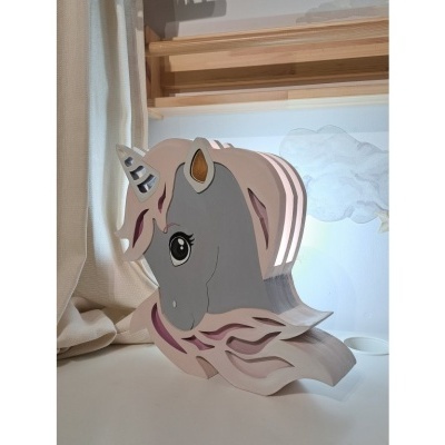 Luminária unicórnio cinzento e rosa sobre mesa branca