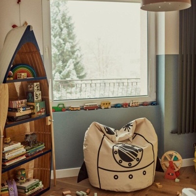 Quarto infantil com pufe estampado, estante em forma de barco, e janela grande