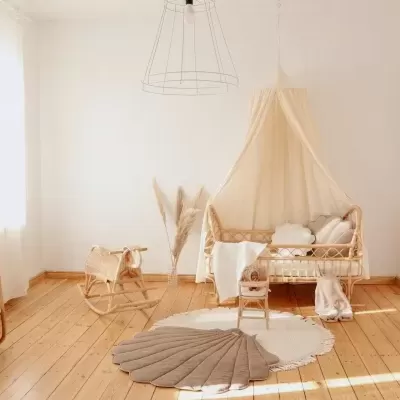 Quarto infantil com berço em madeira clara e dossel bege