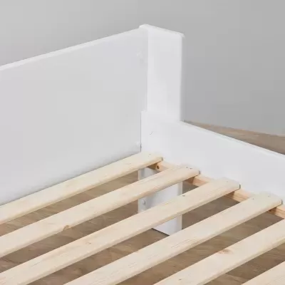 Estrutura de cama branca com ripas de madeira clara sobre chão de madeira.