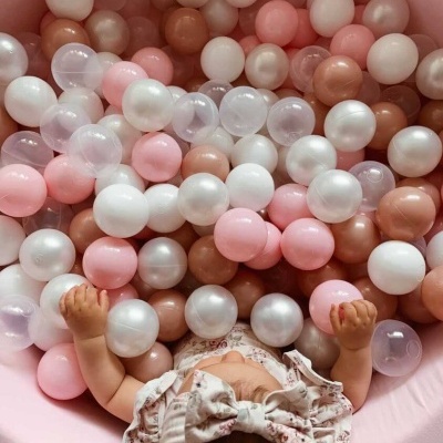 Bebé em piscina de bolas com cores rosa, branco, bege e transparente