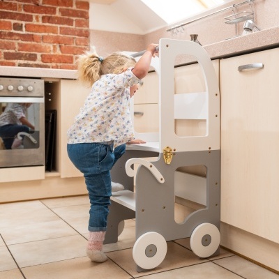 Criança com ajudante de aprendizagem em madeira cinza e branco na cozinha