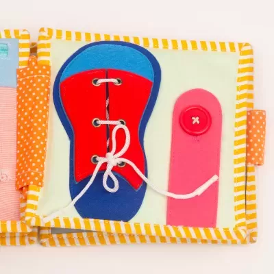 Página de livro de pano infantil com sapato de atacadores e fecho botão coloridos