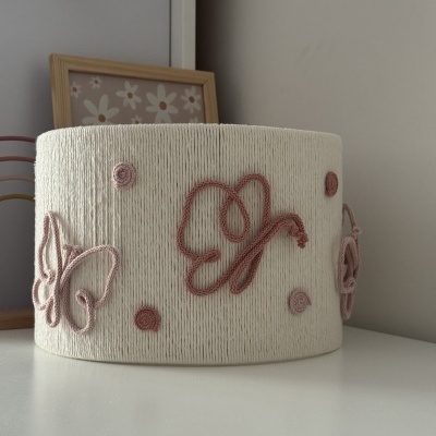 Abajur redondo branco com borboletas e pontos rosa em superfície branca