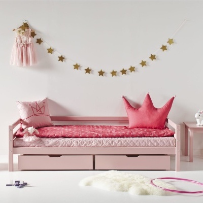 Quarto infantil com cama rosa, almofadas, mesa e cadeira de criança, vestido cor-de-rosa e decoração de estrelas.