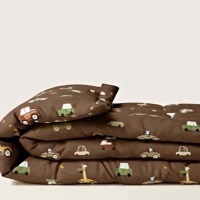 Cobertor infantil macio com padrão de carros e girafas a ser desdobrado.