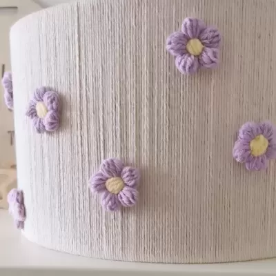 Abajur cilíndrico com flores em crochê roxo e amarelo em base branca texturizada